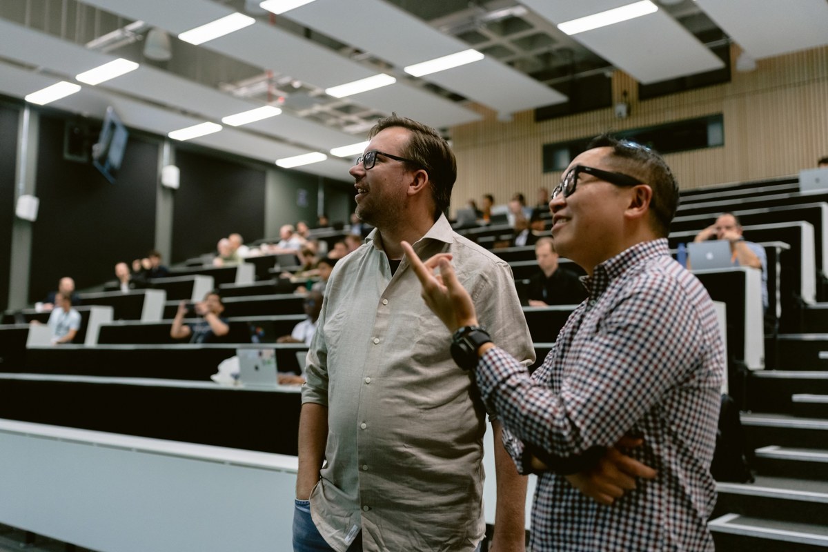 Dux in conversation with an attendee in an auditorium