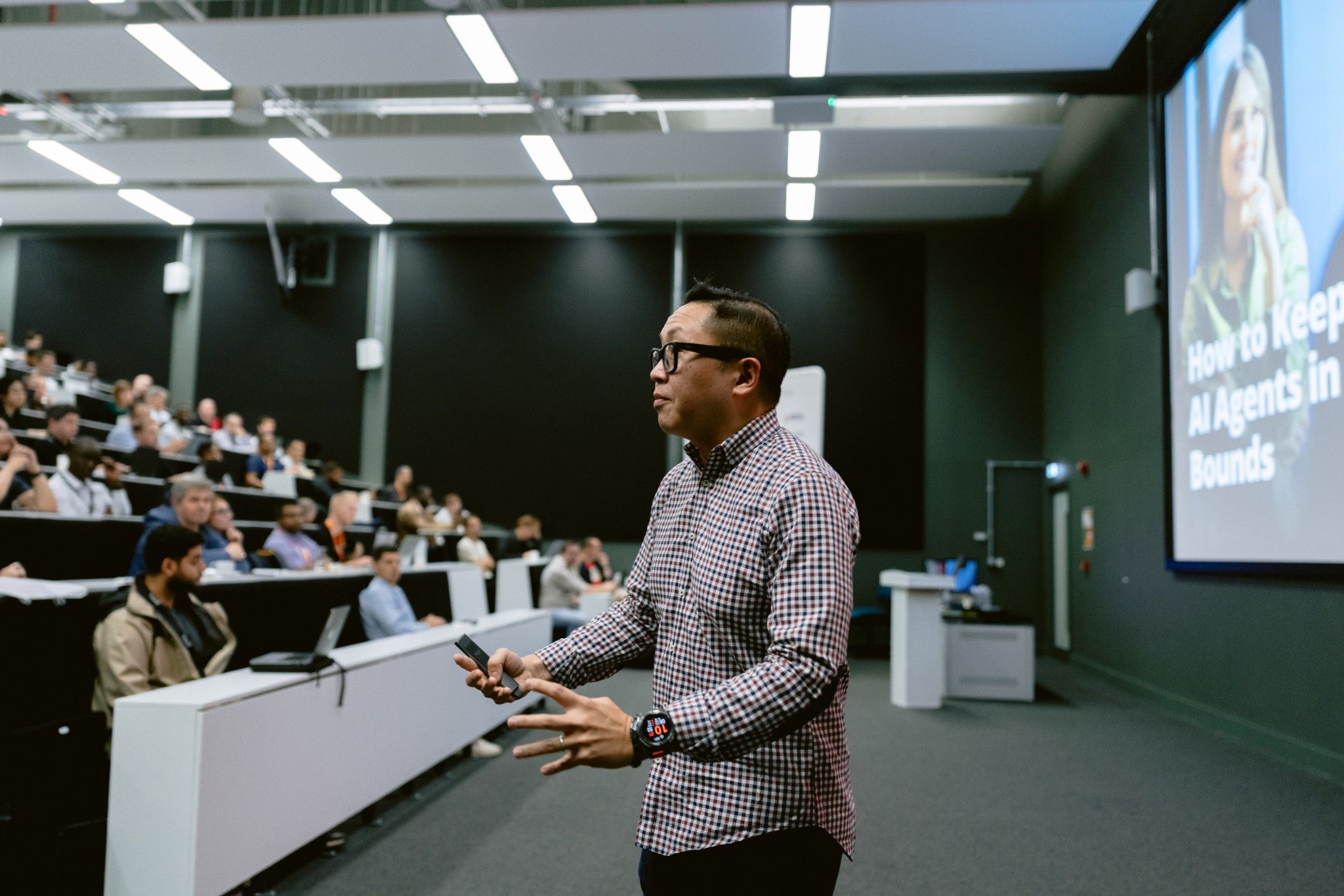 Dux Raymond Sy in a checked shirt, gesturing toward an audience